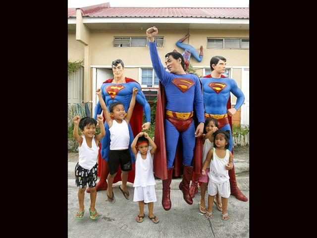 Herbert Chavez poses with his Superman staues with children outside his house in Calamba Laguna, south of Manila.