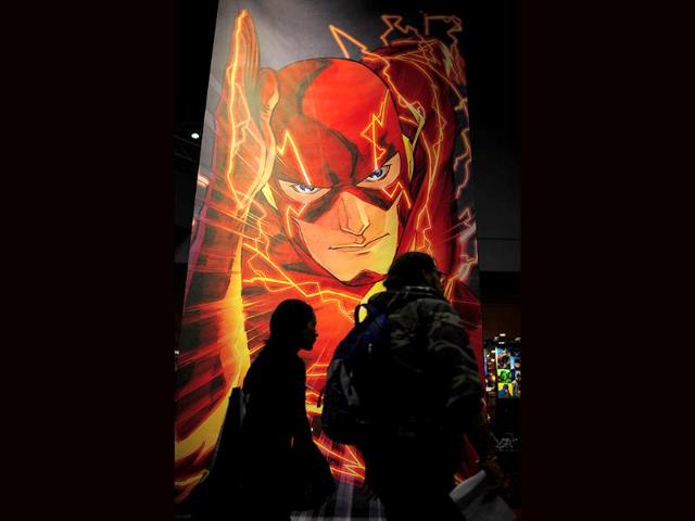 People pass by a poster of comic character Flame displayed at the New York Comic Con, the US East Coast's largest popular culture convention. (AFP)