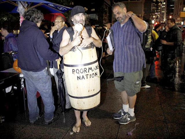 A man wearing a barrel, reports to "Poorman's Nation", a radio talk show, near where the Occupy Wall Street protesters hold meetings at Zuccotti Park in New York.