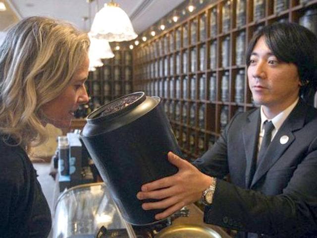 A client smells tea at the counter of French luxury Tea House, Mariage Freres, in the Louvre gallery, under the Louvre Pyramid, central Paris.