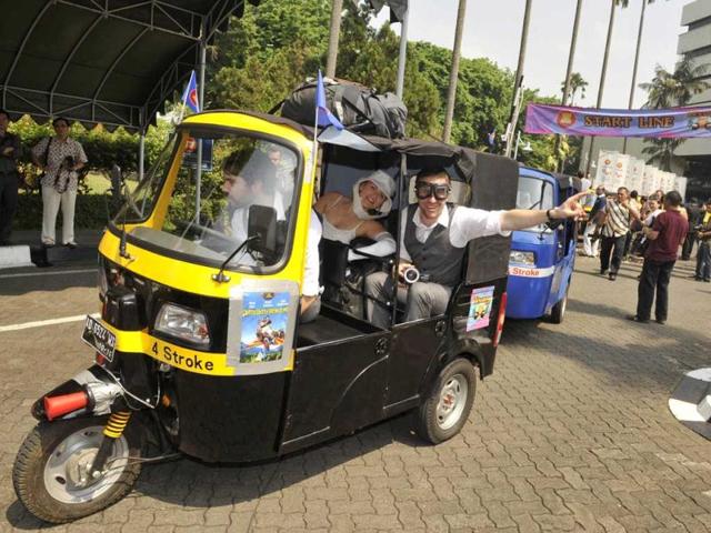 Eoin McPherson (on the wheels) from New Zealand, Kristy Ruthuen (C) and Mark Poot (R) from Australia in their auto-rickshaw start the 3,000-kilometre ASEAN Rickshaw Run in Jakarta.