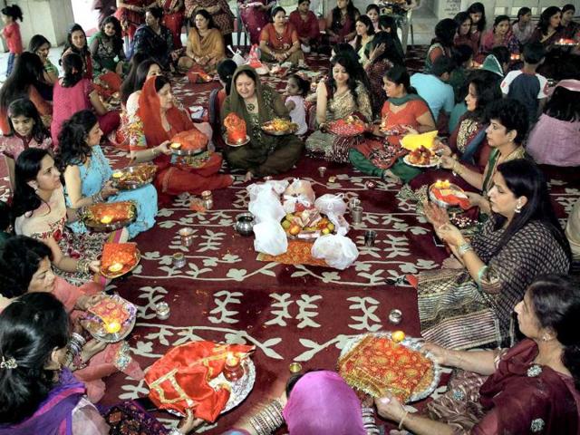 Devotees poses with an earthen lamp as she offers prayers at a temple in Jammu during Karvachauth festival in Jammu on Saturday night.