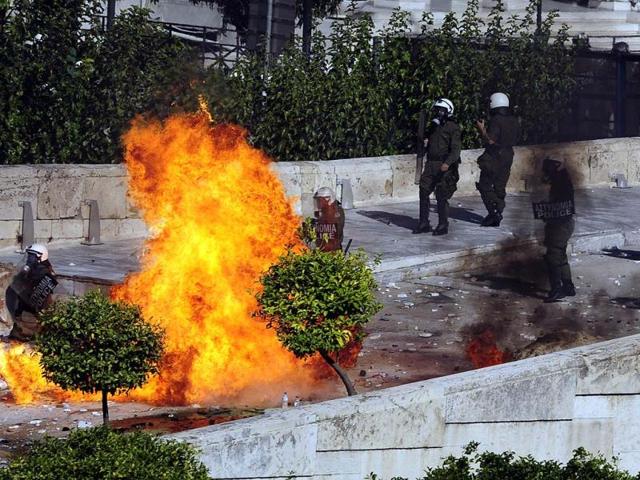 Protesters throw petrol bombs at riot police in front of the Greek Parliament in Athens at the start of a two-day general strike against a new austerity bill.