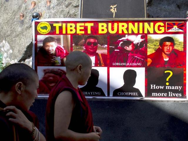Tibetan Buddhist nuns look at a poster showing pictures of those who self-immolated since March in Tibet after a prayer session led by the Dalai Lama in Dharmsala.
