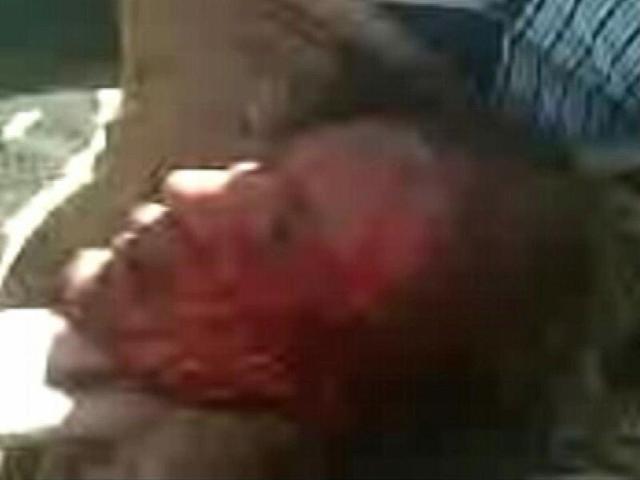 Former Libyan leader Muammar Gaddafi, covered in blood, is held on the ground by NTC fighters in Sirte in this still image taken from video footage.