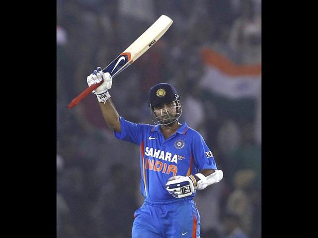 Ajinkya Rahane raises his bat to celebrate scoring his half century during their third one-day international cricket match against England in Mohali.