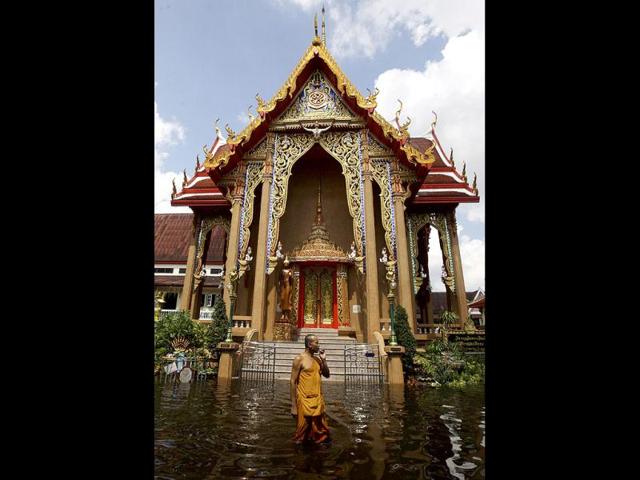 A Thai Buddhist monk smokes a cigarette as he wades along the flooded Weeru Wanaram temple at Don Muang District, in Bangkok, Thailand. Thailand's catastrophic floods may take up to six weeks to recede, Prime Minister Yingluck Shinawatra said.