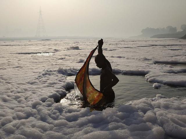 File photo: A devotee wraps a piece of clothing around himself after a ritual dip in the polluted Yamuna river in New Delhi. The world's population will reach 7 bn on October 31, 2011, according to the UN projections. Planet earth is under threat as 7 bn people consume more of the Earth's finite resources.