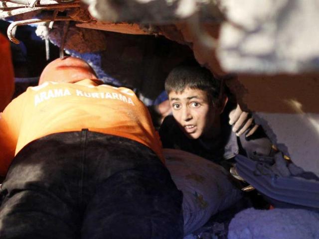 Yunus, a 13-year-old earthquake survivor, waits to be rescued from under a collapsed building by rescue workers in Ercis, near the eastern Turkish city of Van.