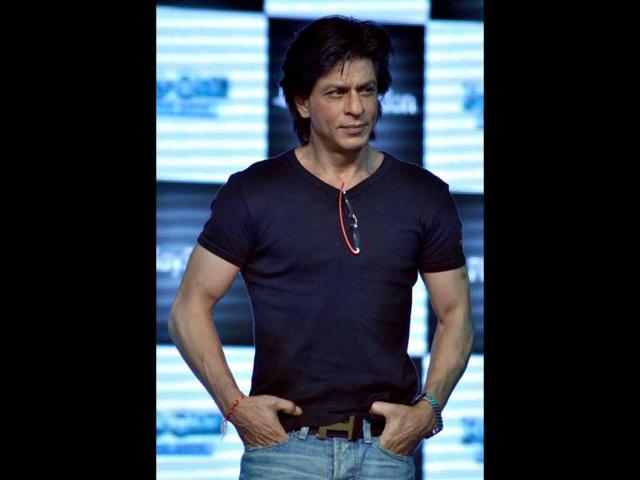 SRK is clad in a black tee over blue denims.