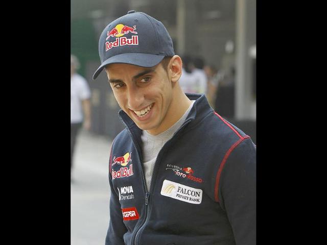 Toro Rosso Formula One driver Sebastien Buemi of Switzerland smiles as he arrives in the paddock area at the Buddh International Circuit in Greater Noida.