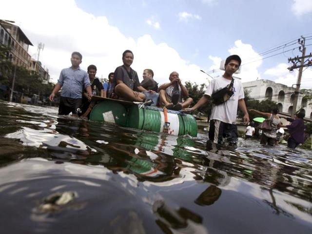 Thai residents ride a makeshift raft as they leave flooded area in Bangkok, Thailand. (AP)