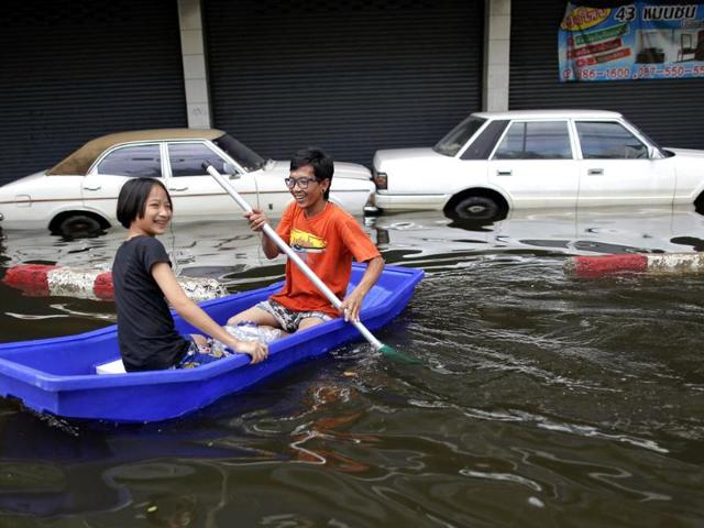 A couple paddle the boat past partially submerged cars in flooded central Bangkok. (Reuters)