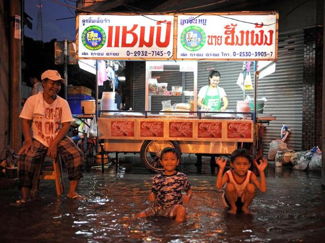 Children play in floodwaters near a street food stall near the Chao Phraya river in central Bangkok. (AFP)