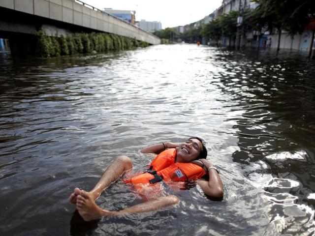 A man wearing a life jacket smiles in floodwaters as floods advance into central Bangkok. (Reuters)