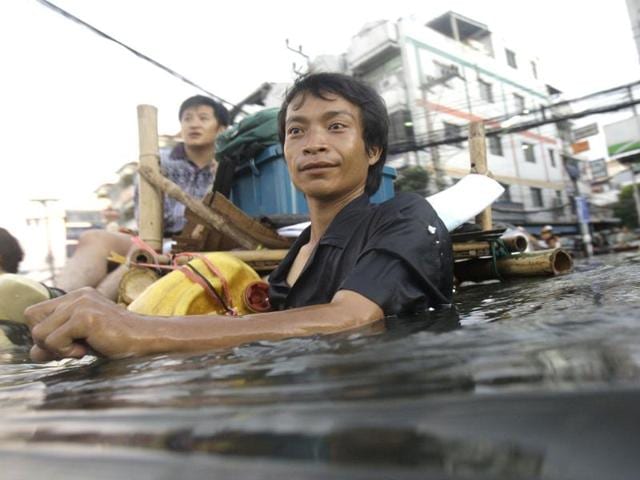 A Thai man wades along chest-deep floodwaters on the outskirts of Bangkok, Thailand. (AP)