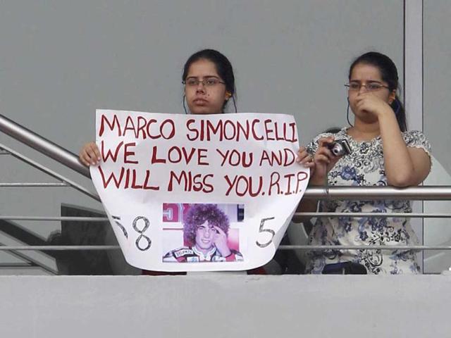 A spectator holds a banner with a photo of Honda MotoGP rider Marco Simoncelli as she watches first practice session ahead of the Indian Formula One Grand Prix at the Buddh International Circuit in Greater Noida on the outskirts of New Delhi. Simoncelli died on Sunday after a crash at the Malaysian MotoGP in Sepang.