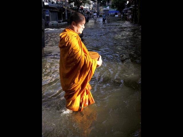 A Buddhist monk walks in a flooded street to collect morning alms in Bangkok. Bangkok's Chao Phraya River is expected to burst its banks over the weekend during the unusually high tide that begins on Friday, causing some flooding in nearby areas. Thailand's worst floods in half a century, caused in part by unusually heavy monsoon rain, have killed 377 people since mid-July and disrupted the lives of nearly 2.2 million, until now mostly in the north and central provinces.