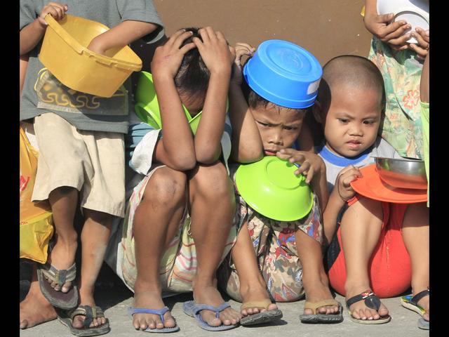 Children hold their food containers as they wait for the distribution of free chocolate porridge at a local government feeding program in Tondo, Manila. The world's population will reach seven billion, according to projections by the United Nations, which says this global milestone presents both an opportunity and a challenge for the planet.
