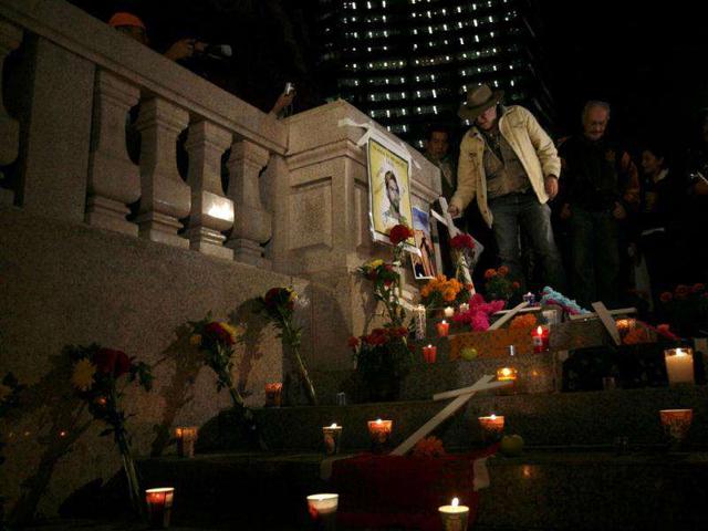 Poet and peace activist Javier Sicilia of the "Peace with Justice and Dignity" movement places a cross next to a photograph at the Angel of Independence monument, where an altar has been created for peace in the country, in Mexico City.