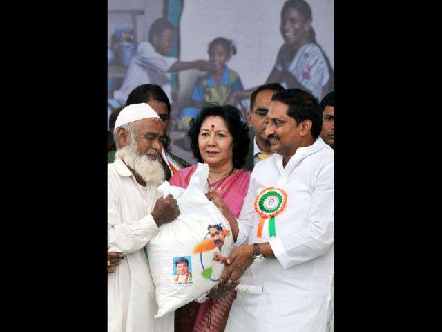 Andhra Pradesh chief minister N Kiran Kumar Reddy (L) presents beneficiary Mohammed Yousuf (L) with a sack of rice to during the launch of 'The One Rupee For A Kilogram Of Rice scheme' during Andhra Pradesh state Formation day in Hyderabad.