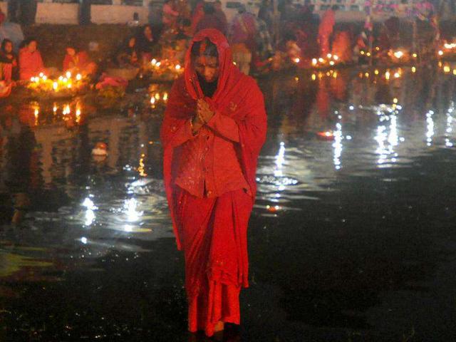 Nepalese Hindu devotees worship the rising sun as they stand in the Rani Pokhari during the Chhath festival, which honours the Sun God, in Kathmandu.