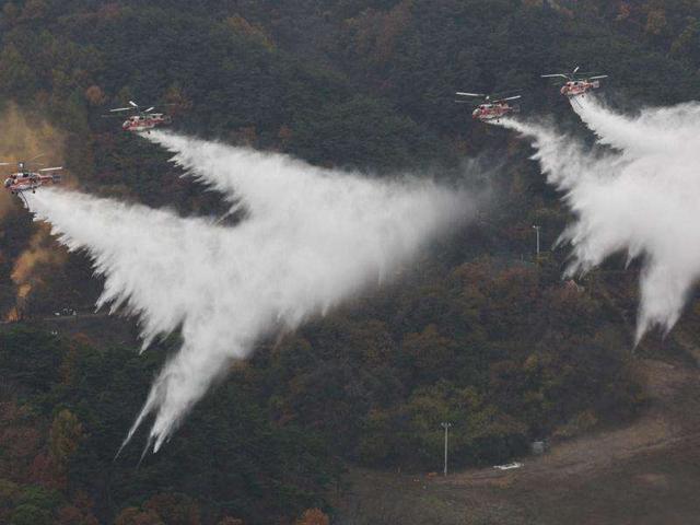 South Korea's forest service helicopters drop water during a forest firefighting joint drill in Chungju. The drill is part of a joint operation involving civilian, military and government personnel.