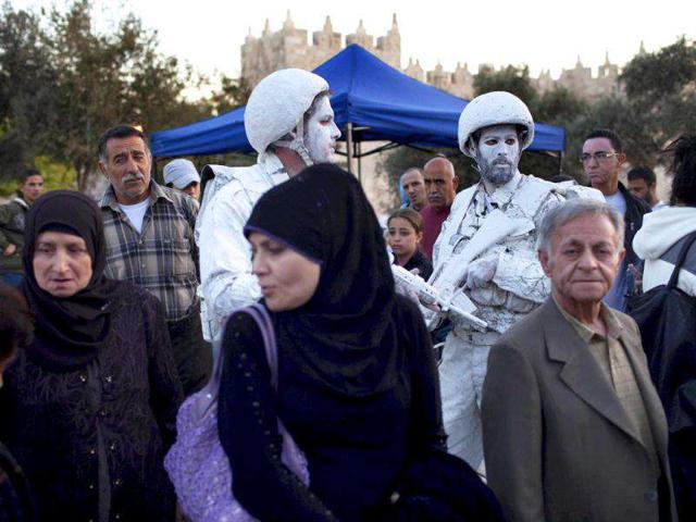Israeli artists Yuda Braun (R) and Jonathan Peleg stand next to Palestinians outside Damascus Gate in Jerusalem's Old City as part of their artistic performance “The White Soldiers patrol Nomansland”.