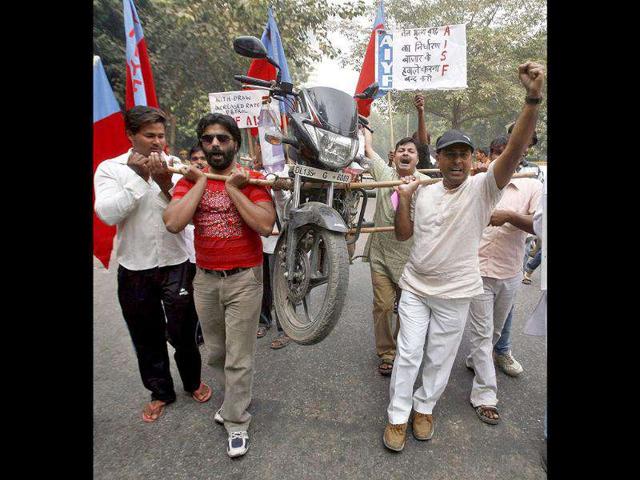 Demonstrators carry a motor bike with the help of bamboo sticks to protest a price hike in petrol in New Delhi. The placard on the right reads "Stop surrendering oil prices to market (forces)".