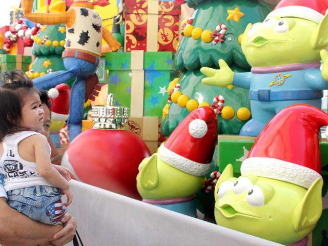 A man holds his daughter to view characters from Disneyland's Toy Story theme outside a shopping mall in Hong Kong. Disneyland's new attraction Toy Story Land, which is based on the popular animated film, is due to open in mid November.