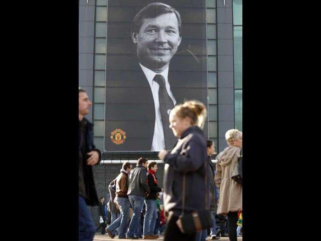 Supporters pass a poster of Manchester United's manager Sir Alex Ferguson commemorating his 25 years in charge of the club before the team's English Premier League soccer match against Sunderland at Old Trafford Stadium, Manchester. (Photo: AP)