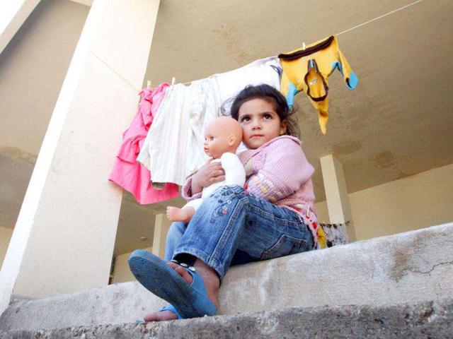 A Syrian refugee girl carries a doll that she received from a women's non-profit charity organization on the first day of Eid al-Adha, at an abandoned school in Wadi Khaled area, northern Lebanon.