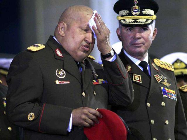 Venezuela's President Hugo Chavez, left, wipes the sweat at his forehead during a ceremony at the military academy in Fuerte Tiuna, Caracas, Venezuela. At right is Venezuela's Defense Minister Gen. Carlos Mata.