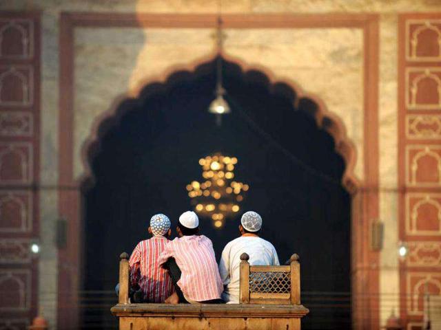 Three boys sit near an entrance to the inner courtyard of the 17th century Jama Masjid mosque in New Delhi as they wait for morning Eid al-Adha prayers.