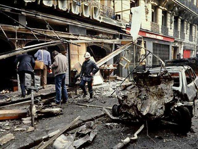 People walk past the wreckage of the bombed car that exploded the day before in Rue Marbeuf, near Champs Elysées in Paris on April 23, 1982. The attack is attributed to Ilich Ramirez Sanchez, aka Carlos the Jackal. (File Photo)