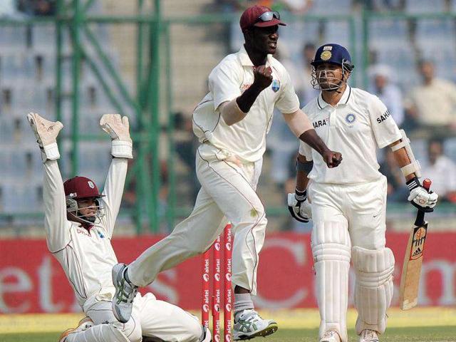 West Indies captain Darren Sammy (C) and wicket keeper Carlton Baugh (L) celebrate the dismissal of Sachin Tendulkar (R) during the fourth day of the first cricket test match between India and the West Indies in New Delhi.