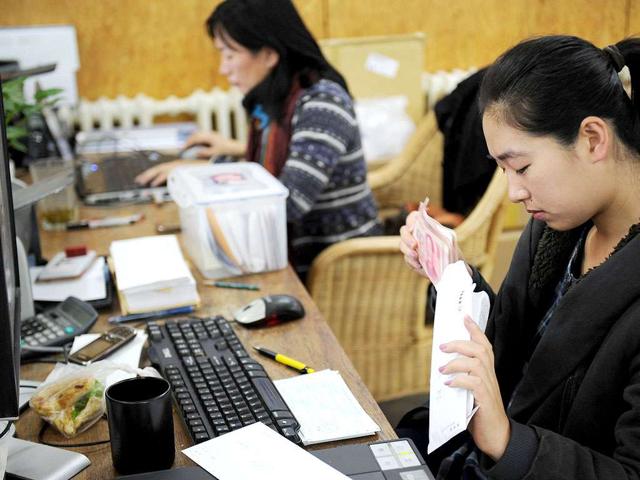 Staff of Chinese artist Ai Weiwei count cash donations at his studio in Beijing. Thousands of people have so far donated 5.29 million yuan (830,000 USD) to help Ai Weiwei pay a huge tax fine, with some throwing money wrapped in paper planes into his garden, the Chinese artist said.