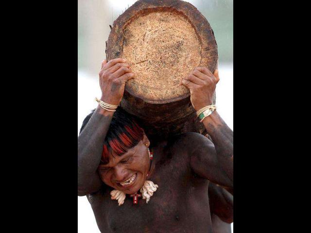 A Xavante Indian carries a tree trunk during a team race at the Indigenous Games on the island of Porto Real in the city of Porto Nacional, Brazil.