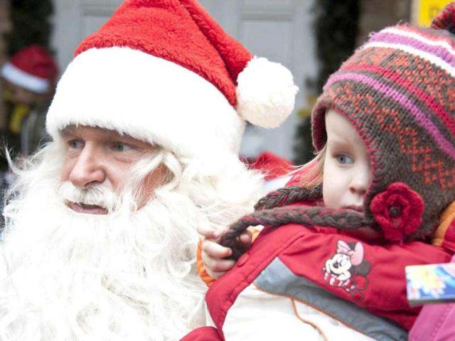 A man dressed up as Santa Claus holds a young child in front of the Santa Claus post office in the Eastern German town of Himmelpfort (Heaven's Gate). Children can send their Christmas wish lists to Himmelpfort from around the world and receive a reply from Santa. AFP Photo / John Macdougall