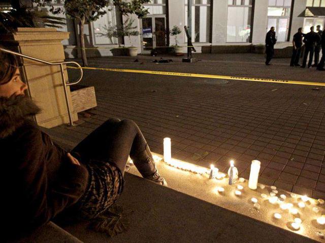 An Occupy Oakland protestor sits beside candles at the scene of a shooting on Thursday, in Oakland, Calif. AP
