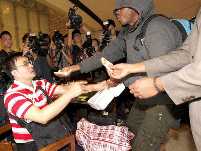 African nationals grab a pack of five Apple's iPhone 4S and refuse to accept the money they were offered earlier as they argue with a dealer outside an Apple Store in Hong Kong. Reuters