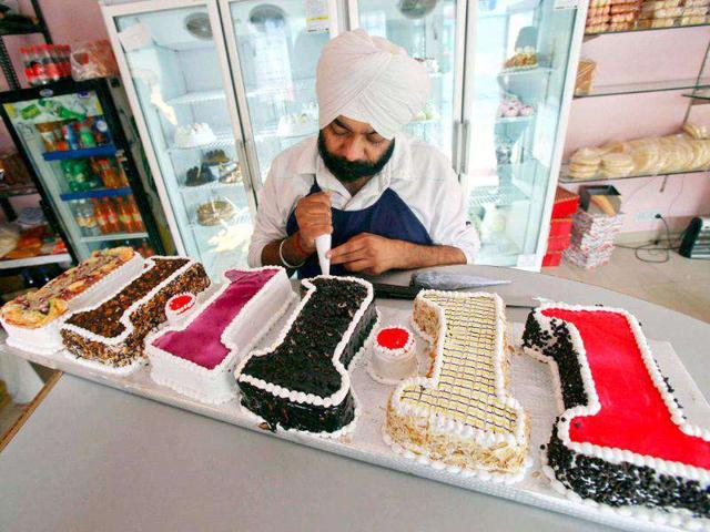 A man applies finishing touches to a cake read "11.11.11" at a bake shop in Panchkula.