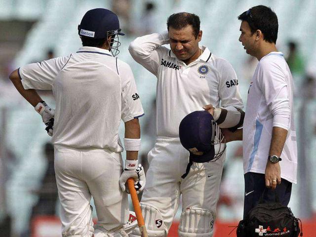 Virender Sehwag (C) grimaces in pain as he receives treatment after being hit by a ball during the second Test cricket match in Kolkata.