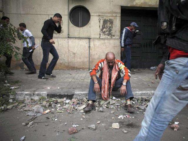 A protester overcome with tear gas inhalation sit on the curb during clashes with the Egyptian riot police, not seen, near the interior ministry in downtown Cairo, Egypt. Firing tear gas and rubber bullets, Egyptian riot police clashed with thousands of rock-throwing protesters demanding that the ruling military quickly announce a date to hand over power to an elected government. AP Photo