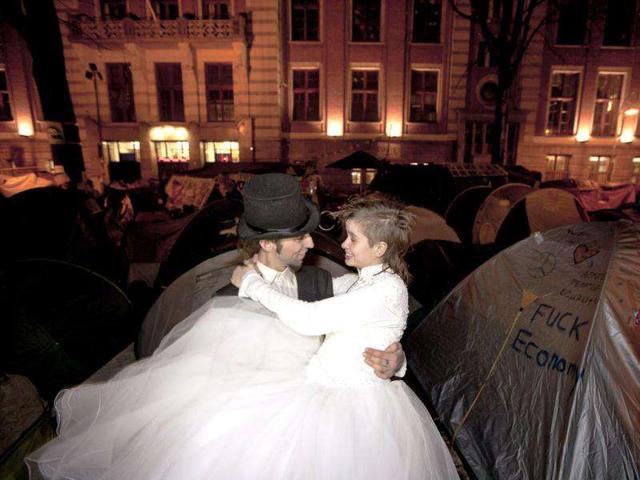 Gijs Peskens (L) carries his wife Eveline Constance Heijkamp, both Occupy Amsterdam demonstrators, to their tent on the Beursplein after getting married in Amsterdam.