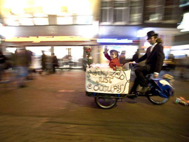 Newly-weds Eveline Constance Heijkamp (L) and Gijs Peskens, Occupy Amsterdam demonstrators, leave on a bicycle after getting married on the Beursplein in Amsterdam.