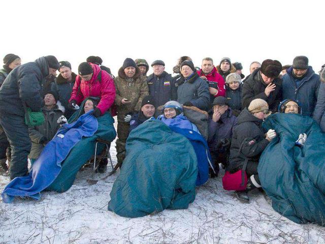 Russia's space agency ground personnel crowd near three astronauts, (L-R) American Mike Fossum, Russia's Sergei Volkov and Japan's Satoshi Furukawa, shortly after their landing in Soyuz TMA-02 capsule near the town of Arkalyk in northern Kazakhstan. AFP Photo / Shamil Zhumatov