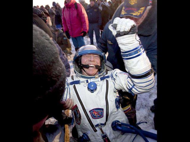 Ground personnel help member of the ISS crew US astronaut Michael Fossum to get out off the Soyuz capsule minutes after landing near the town of Arkalyk, northern Kazakhstan. AP Photo/Sergei Remizov