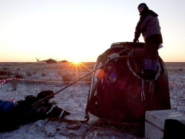 A specialist stands on the Soyuz TMA-02M spacecraft after it landed near the town of Arkalyk, northern Kazakhstan. AP Photo/Sergei Remizov