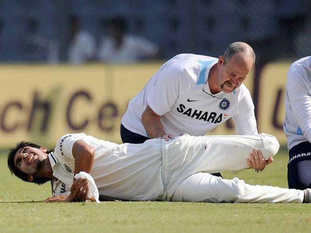 A physiotherapist helps Ishant Sharma (on ground) to stretch during the second day of the third test cricket match between India and West Indies at the Wankhede stadium in Mumbai.